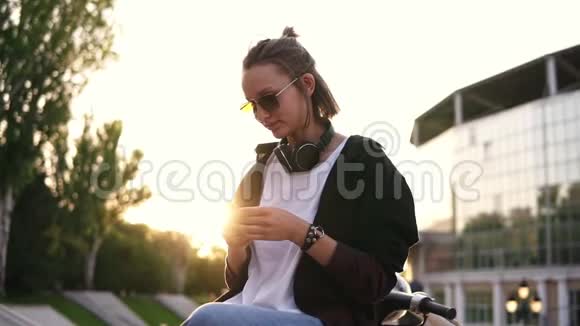 低角度镜头一个忧郁的女孩坐在户外的街道或公园她的智能手机在手中a的概况视频的预览图