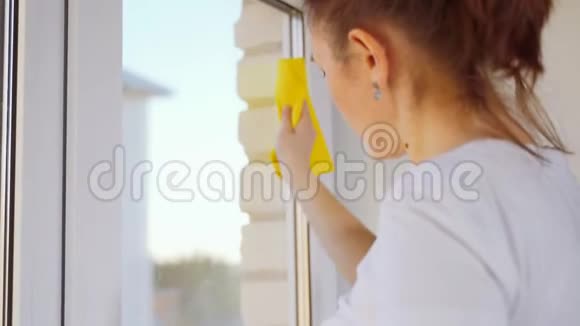 一个女人用黄色的抹布擦窗户洗房子的窗户视频的预览图