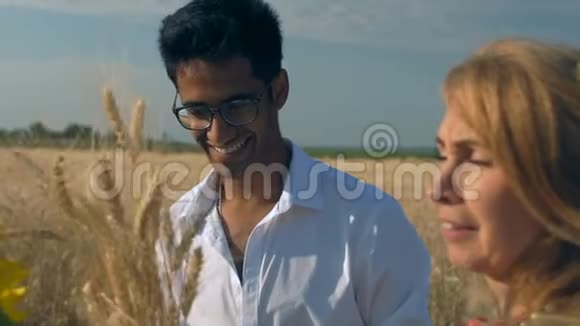 特写镜头慢镜头戴眼镜的印度男人微笑着接近成年女人他刚带了一束麦穗视频的预览图