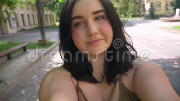 美丽肥胖的年轻女性她在手机上用网络摄像机自拍或拍摄视频站在附近的街道上视频的预览图