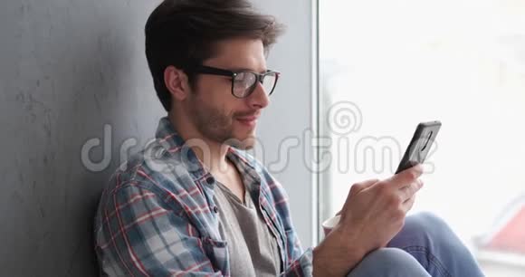 放松的男人在家里用手机视频的预览图