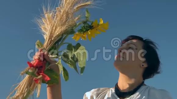 特写慢动作美丽的女性穿着国家服装欣赏一束麦穗和持着的向日葵视频的预览图