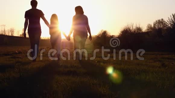 日落时分父母和女儿散步的剪影视频的预览图