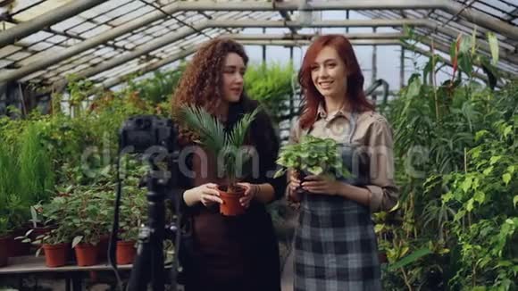 微笑的女博客和穿着围裙的园丁们手捧鲜花一边聊天一边在网上录制视频博客视频的预览图