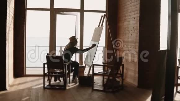 一位成年画家在他的车间里从事一幅大画布上的绘画视频的预览图