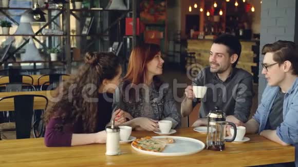 朋友们在咖啡馆里庆祝团圆喝饮料和比萨饼敲杯子喝酒和分享新闻友谊视频的预览图