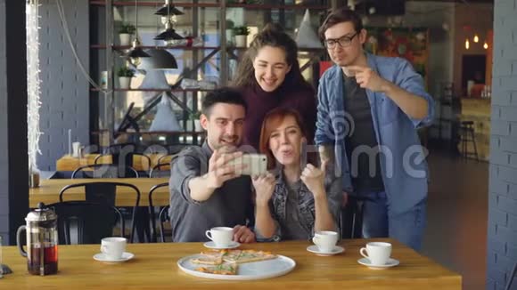 快乐的年轻人流行的博客写手正在自拍假装笑着在咖啡馆里玩得很开心现代技术视频的预览图