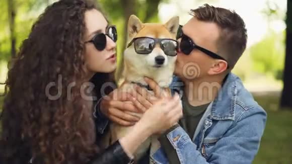 可爱的一对帅哥和他的女朋友正在亲吻血统狗他们都戴着太阳镜人们笑着说视频的预览图
