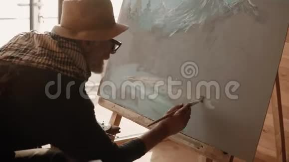 画家在画架上用画笔绘制油画视频的预览图