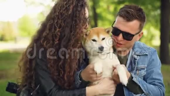 快乐的年轻人在公园里和漂亮的狗玩玩得既开心又开心一头长卷发的漂亮女孩视频的预览图