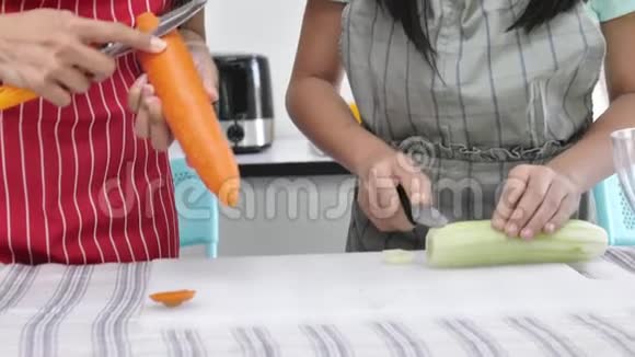 微笑的亚洲母亲和女孩在厨房的碗里准备沙拉微笑着面对视频的预览图