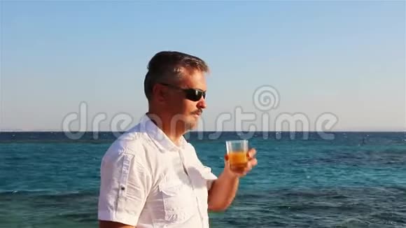 一个人从杯子里喝着美味的橙汁视频的预览图