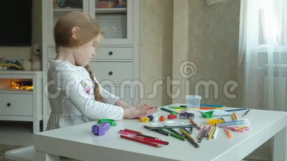 一个小女孩玩橡皮泥用手把它卷起来在上面剪一个图形图形和彩色铅笔视频的预览图
