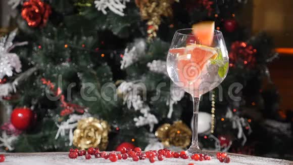 新年和圣诞快乐的餐桌概念杯子里放一杯鸡尾酒里面放一根稻草背景是一棵毛皮树视频的预览图