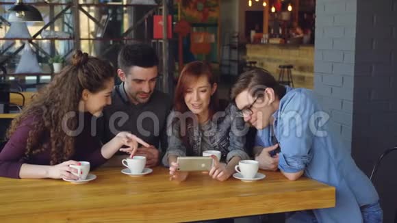 快乐的学生正在看有趣的视频讨论它并在咖啡馆见面时大笑快乐的人现代的视频的预览图