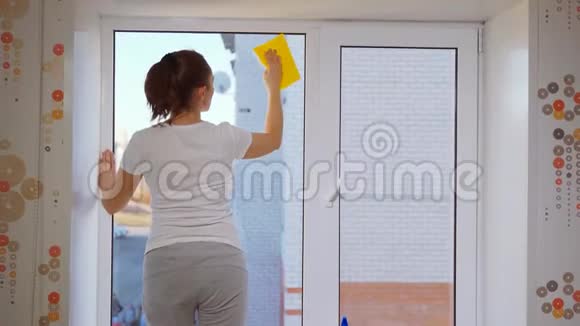 一个女人用黄色的抹布擦窗户洗房子的窗户视频的预览图