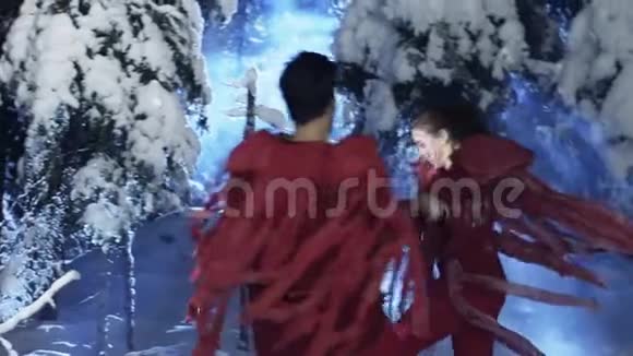 穿着红色衣服的白种人男女正在雪地的冬天的树林里跳舞视频的预览图
