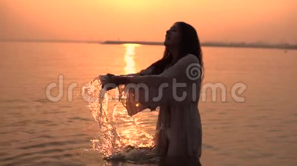 在阳光的映衬下女孩在河里溅起美丽的花视频的预览图
