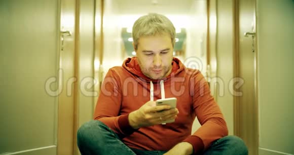 灰发青年穿着休闲装在酒店走廊用智能手机视频的预览图