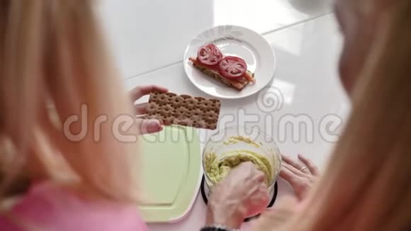 金发女郎用菜刀用浅绿色鳄梨酱涂吐司视频的预览图