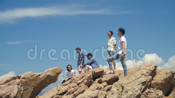 年轻的亚洲成年男子站在海边的岩石上视频的预览图