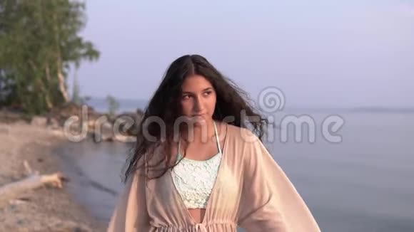 一个穿着沙滩长袍的漂亮女孩沿着海边散步慢动作高清高清视频的预览图
