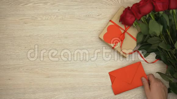 在背景上用礼物和玫瑰做我的情人节短语手拿信封视频的预览图