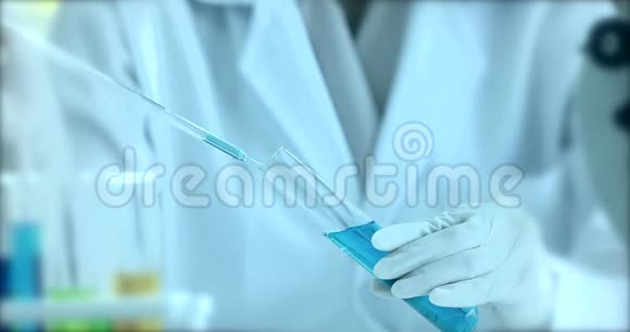 在实验室里做实验的那位模糊的科学家她把蓝色的液体滴到试管里放着五颜六色的试管视频的预览图