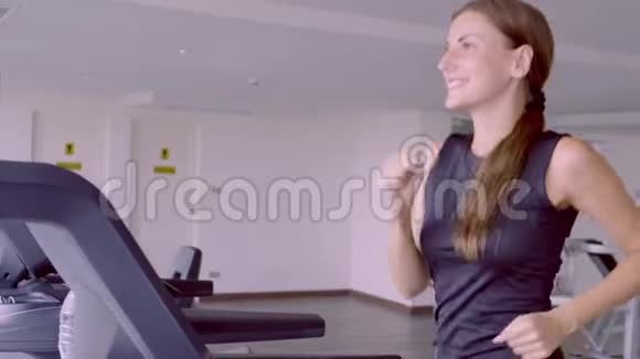 漂亮的健身女孩在健身房跑步机上跑步和喝水视频的预览图