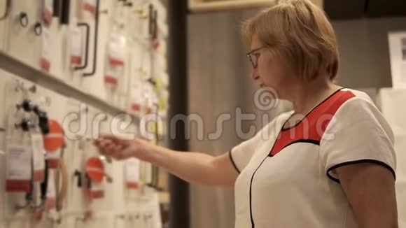 一位老妇人正在检查家具的配件固定在商店的展台上视频的预览图
