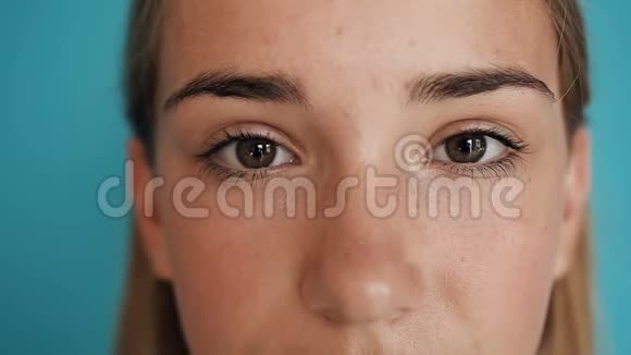 一张可爱的女孩脸女孩睁开眼睛微笑着孤立在蓝色背景上肖像摄影视频的预览图