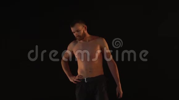 肌肉男赤裸着上身站在黑色背景下视频的预览图