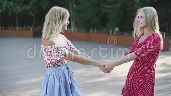 两个漂亮的金发女朋友在公园里玩得很开心修女们跳圆舞曲慢动作视频的预览图