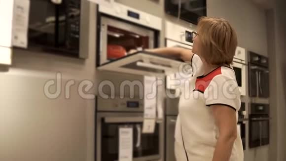 退休妇女正在零售商店寻找烤箱打开门视频的预览图