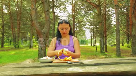 一个坐在木桌上的公园里的女人倒了一份柠檬汁水果沙拉来野餐视频的预览图