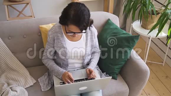 穿灰色羊毛衫的成熟女人坐在沙发上视频的预览图