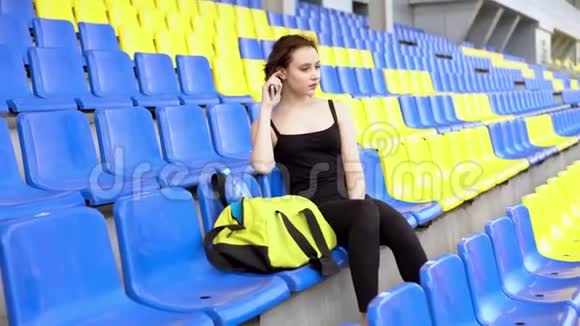 年轻漂亮的女人坐在体育场论坛上视频的预览图