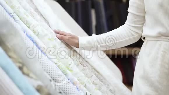 一个漂亮的女孩在布料店购物她在光线范围内选择了一卷带有圆点的织物视频的预览图