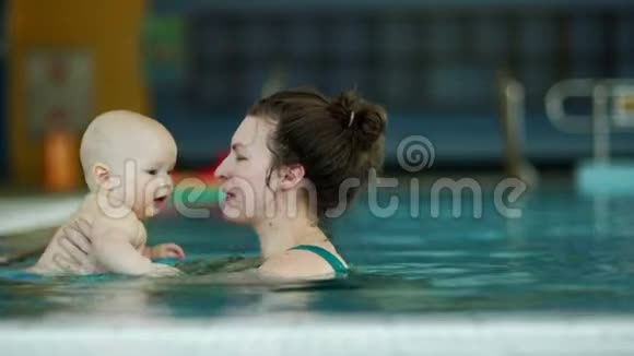 年轻的母亲教她那岁的婴儿在游泳池里潜水这孩子很高兴儿童发展母亲节视频的预览图