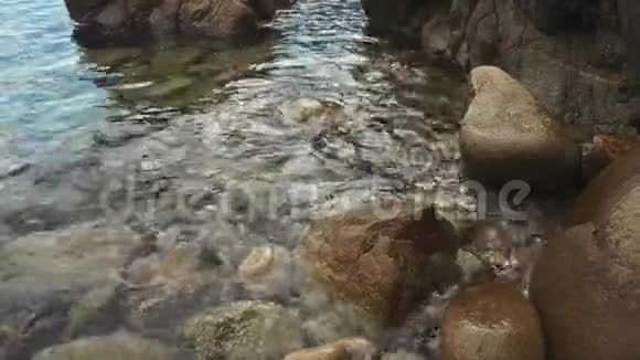 清澈的海水溅在岸上的大石头上近景视频的预览图