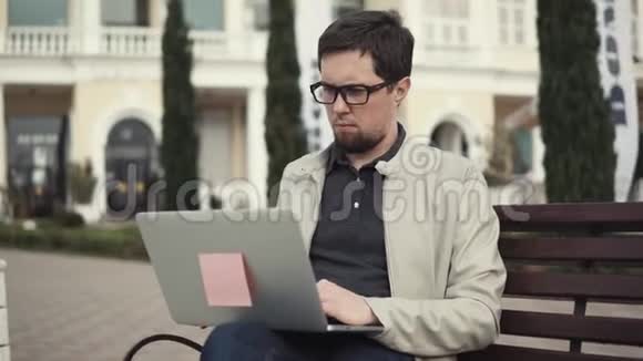 严肃的成年人坐在长凳上用笔记本上网视频的预览图