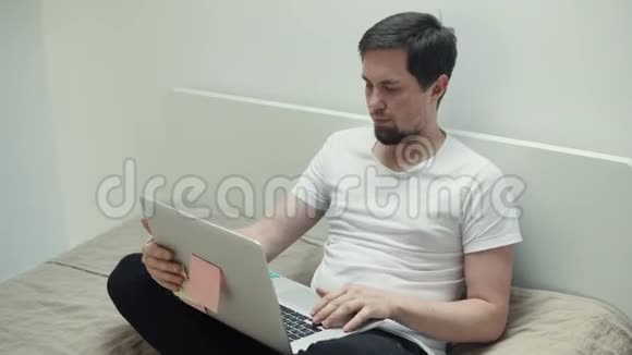 布鲁纳曼晚上坐在床上在家里用笔记本电脑工作视频的预览图