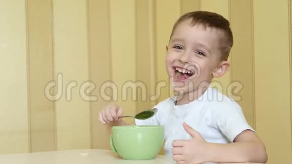 孩子高兴地笑着用勺子从盘子里吃汤坐在桌子旁视频的预览图