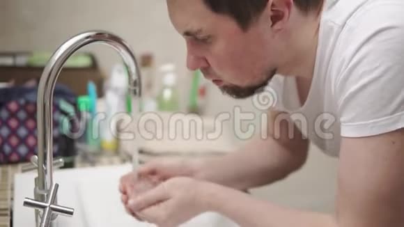 一位成年男子早上正在浴室的水槽上方洗脸特写镜头视频的预览图