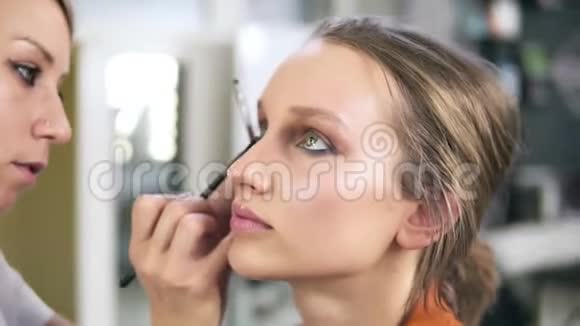 化妆室专业的化妆师弥补了一个美丽的高加索模特抹些眼影视频的预览图