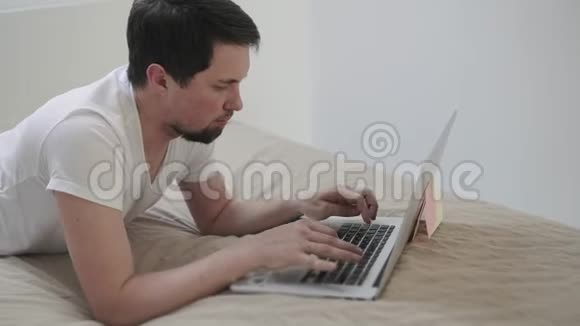 一个人正按着笔记本上的按键躺在卧室的床上视频的预览图