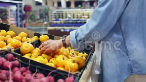 一个女孩从蔬菜部门的盒子里挑选新鲜的黄色番茄的录像杂货店女孩补充视频的预览图