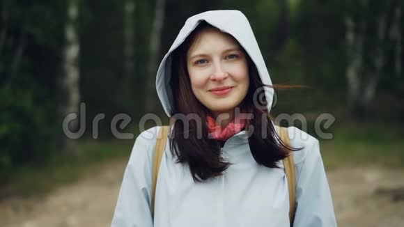 慢镜头描绘迷人的年轻女子微笑着看着摄像机站在森林里绿树成荫视频的预览图