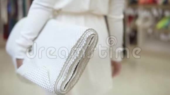 穿着白色衣服的时髦年轻女人穿着布卷穿过纺织店带圆点的白色视频的预览图