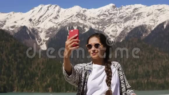 一位女士正在雪山背景下的智能手机上拍照视频的预览图